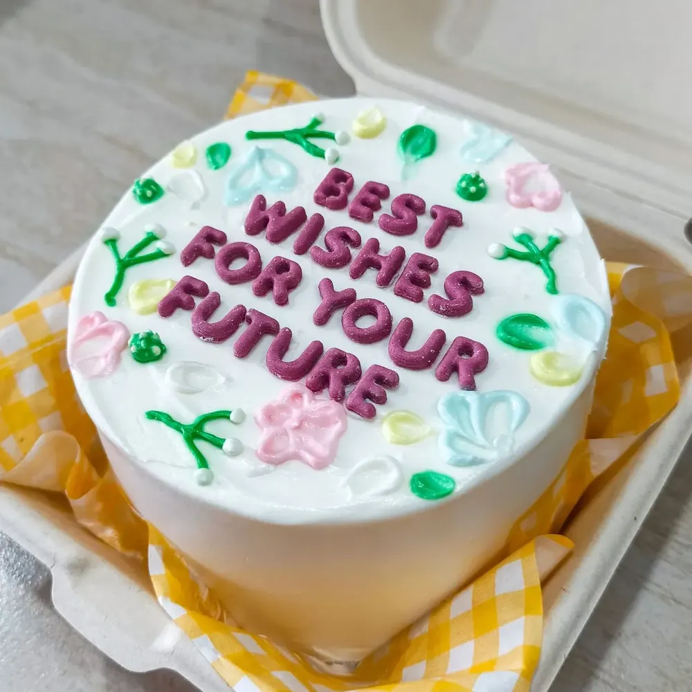 A bento cake piped with the message Best wishes for your future, with flowers and leaves