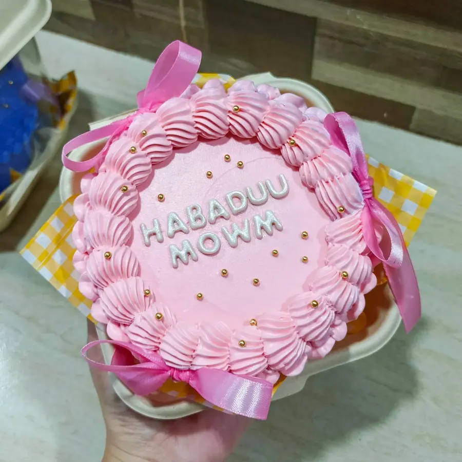 A pink bento cake with piped shell borders, pearl sprinkles and a fondant name
