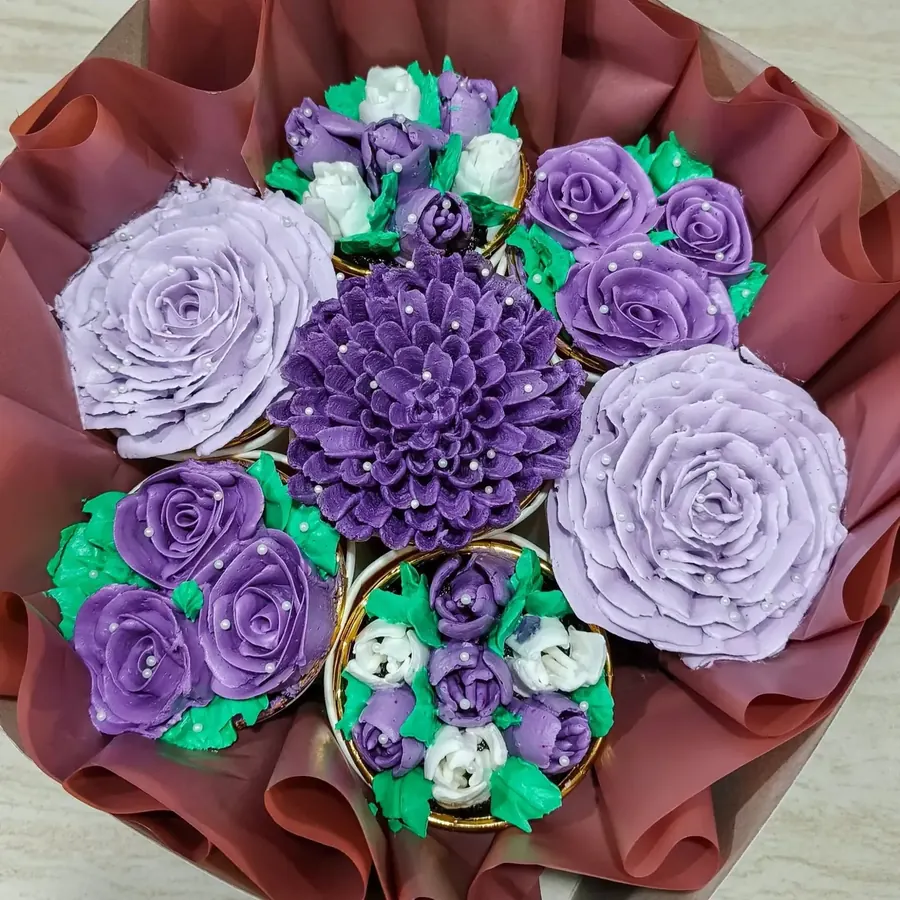 A cupcake bouquet of purple and lavender buttercream flowers wrapped in paper